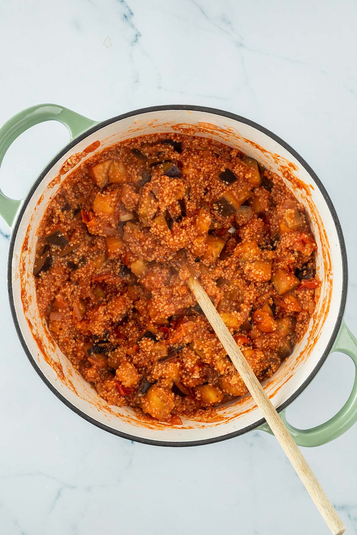 Vogelperspektive auf eine Couscous-Gem&uuml;se-Pfanne mit Tomatensauce in einem breiten Topf.
