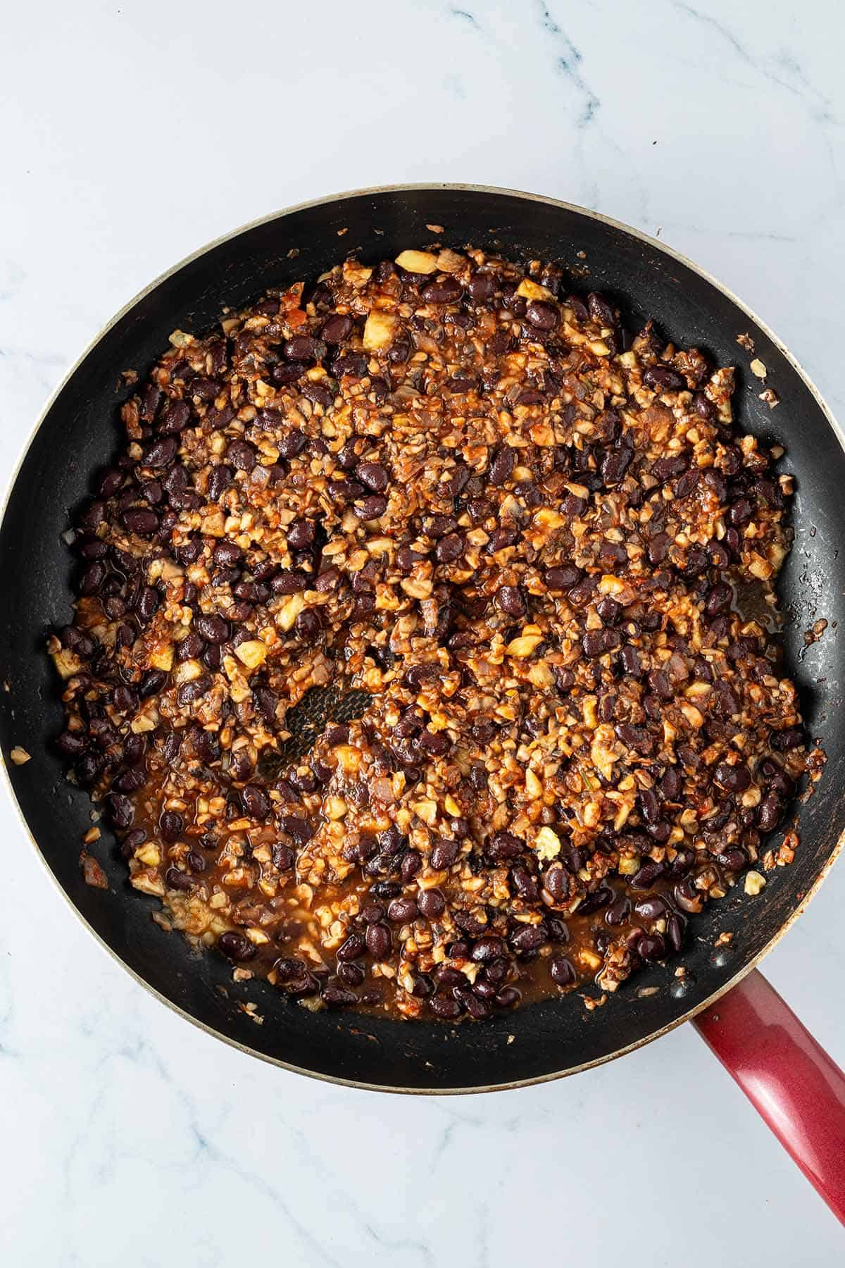 Schwarze Bohnen und fein gehackte Champignons, Waln&uuml;ssen, Ananas und Salsa k&ouml;cheln f&uuml;r die Taco-F&uuml;llung in einer Pfanne.