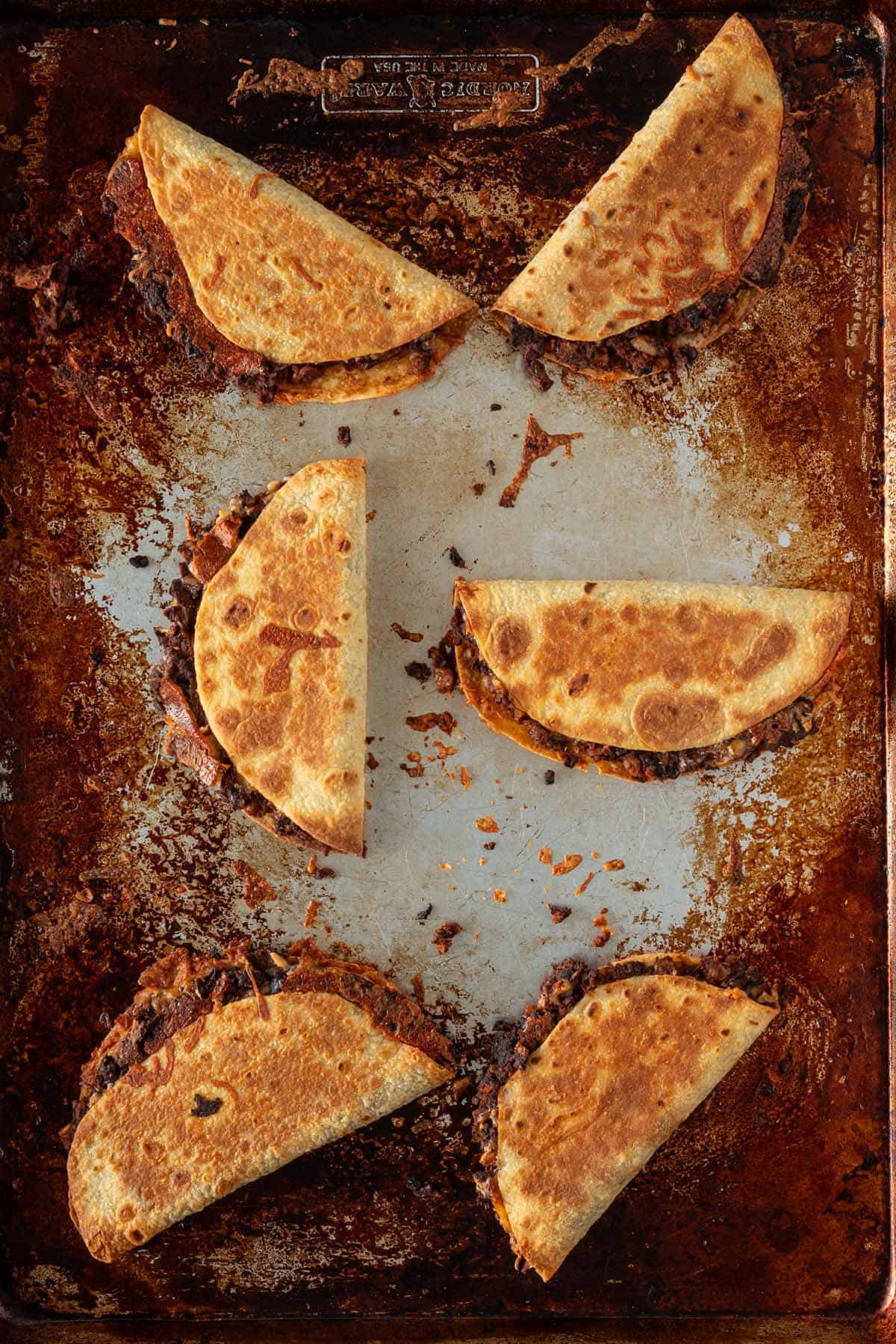 Goldbraun gebackene Crispy Tacos mit schwarzer Bohnenf&uuml;llung auf einem Backblech.