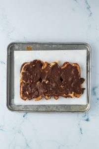 Dattelriegel mit fester Schokolade auf einem kleinen Blech mit Butterpapier.