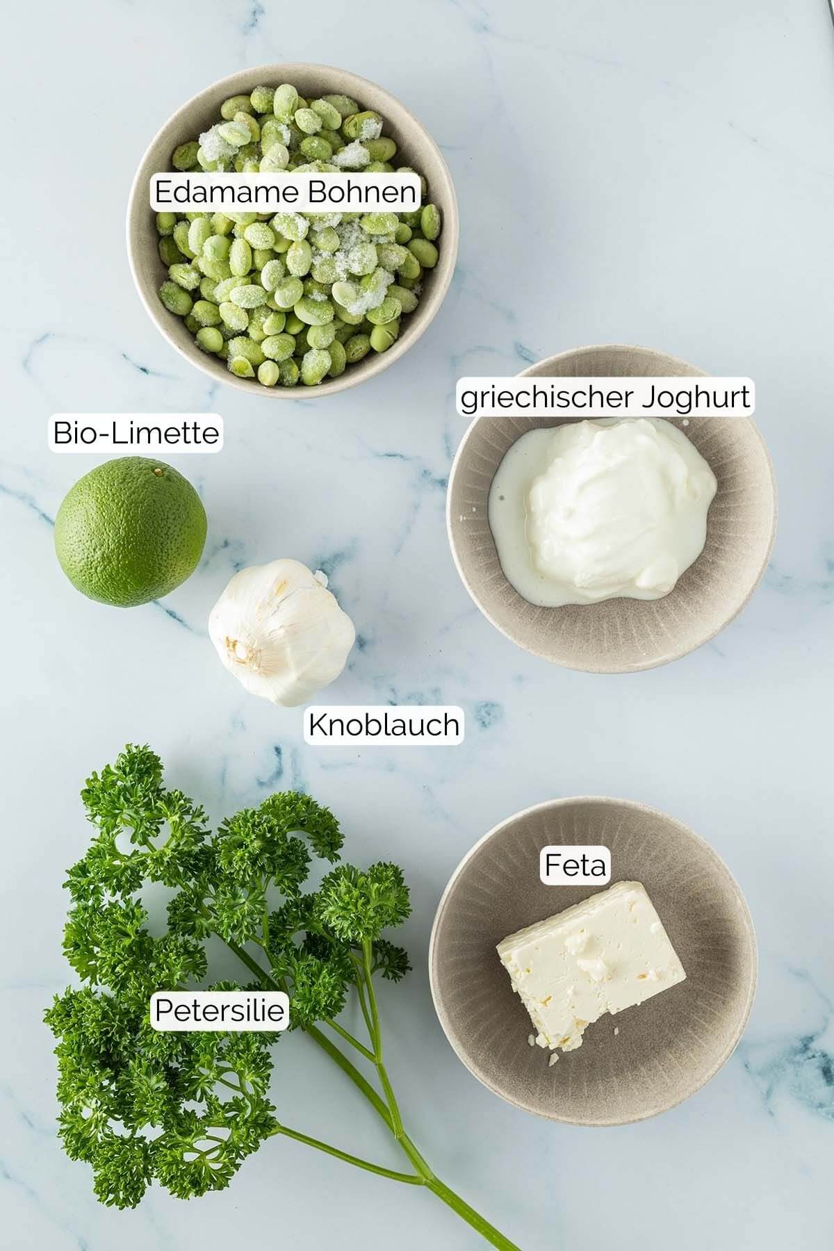 Bild alle Zutaten mit jeweiligen Textbeschriftungen, die f&uuml;r den Edamame Dip ben&ouml;tigt werden.