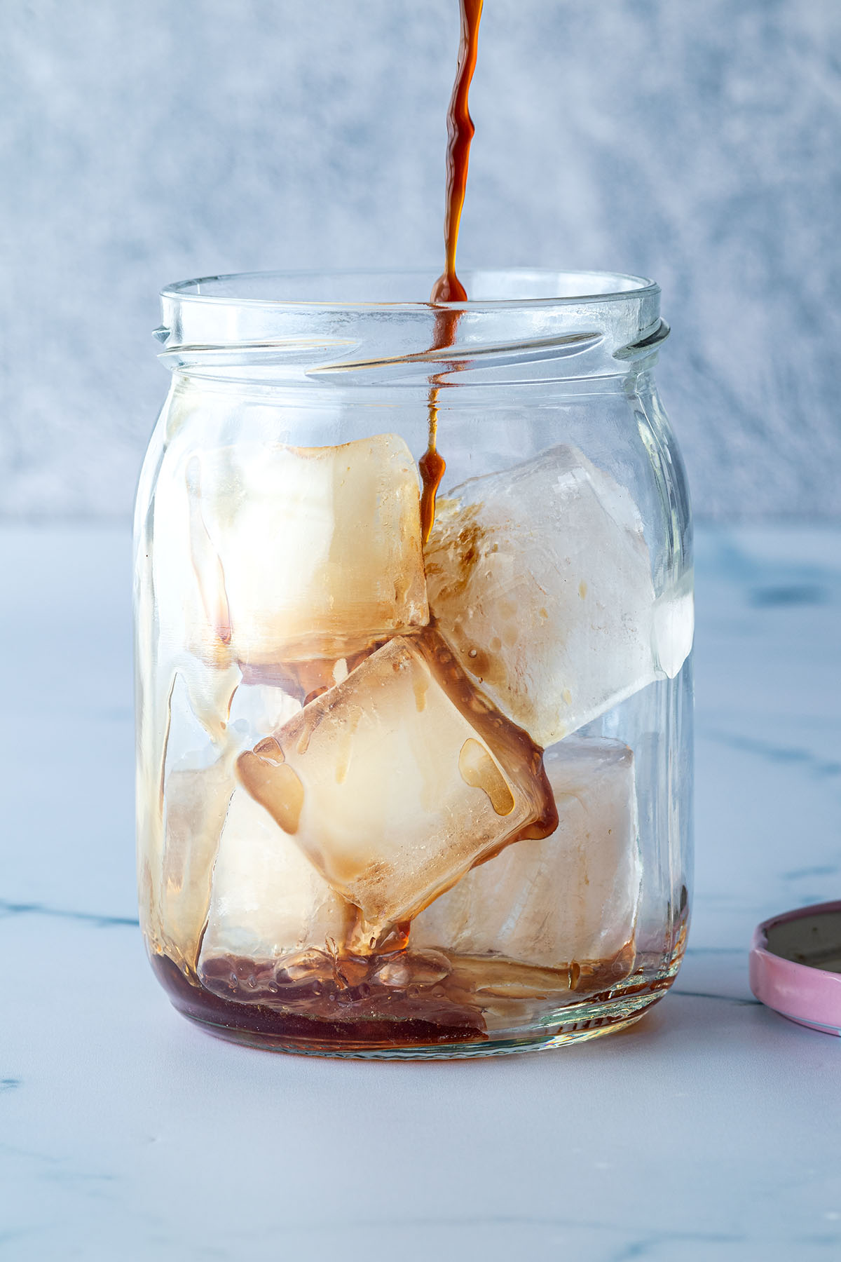 Kaffee wird in ein mit Eisw&uuml;rfeln gef&uuml;lltes Schraubglas gef&uuml;llt.