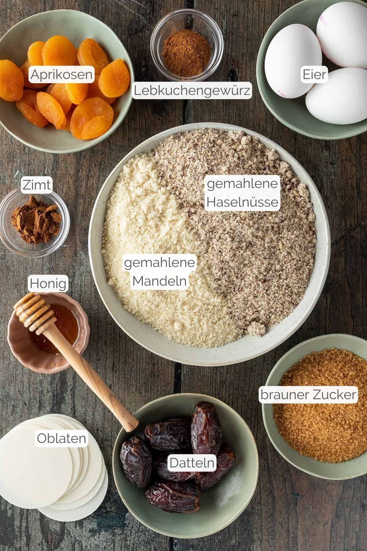Alle Zutaten mit jeweiligen Textbeschriftungen, die f&uuml;r saftige Elisenlebkuchen ben&ouml;tigt werden.
