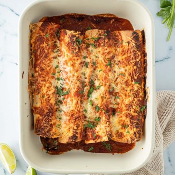 Vogelperspektive auf eine Auflaufform mit K&auml;se &uuml;berbackenen Enchiladas, Deko im Bildrand.