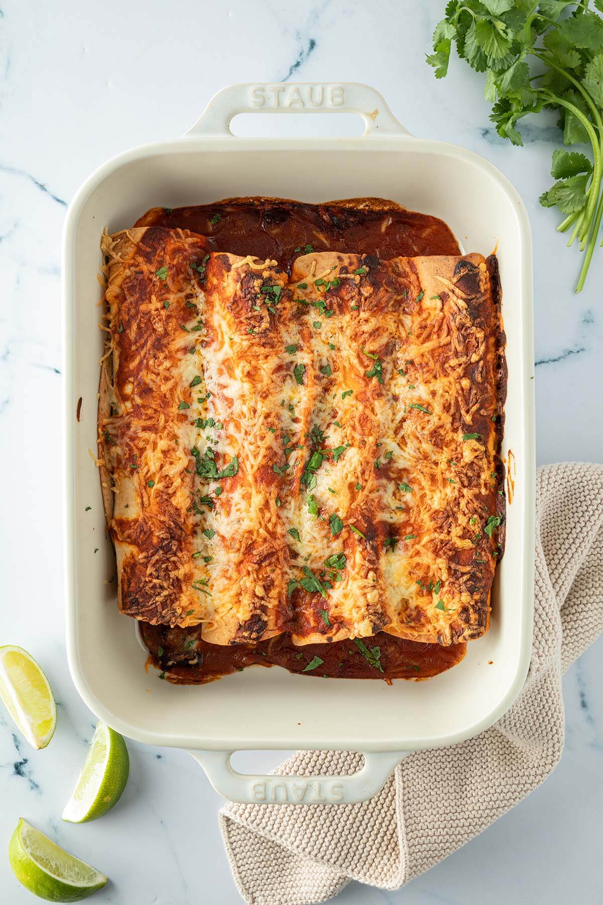 Vogelperspektive auf eine Auflaufform mit K&auml;se &uuml;berbackenen Enchiladas, Deko im Bildrand.