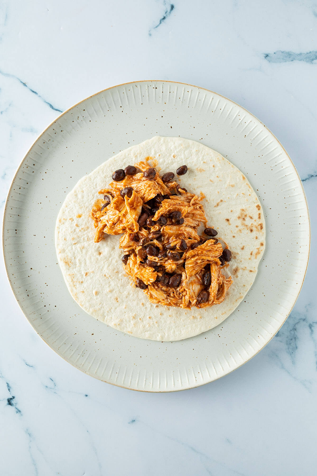 H&auml;hnchen-Bohnen-F&uuml;llung auf einem kleinen Weizentortilla.