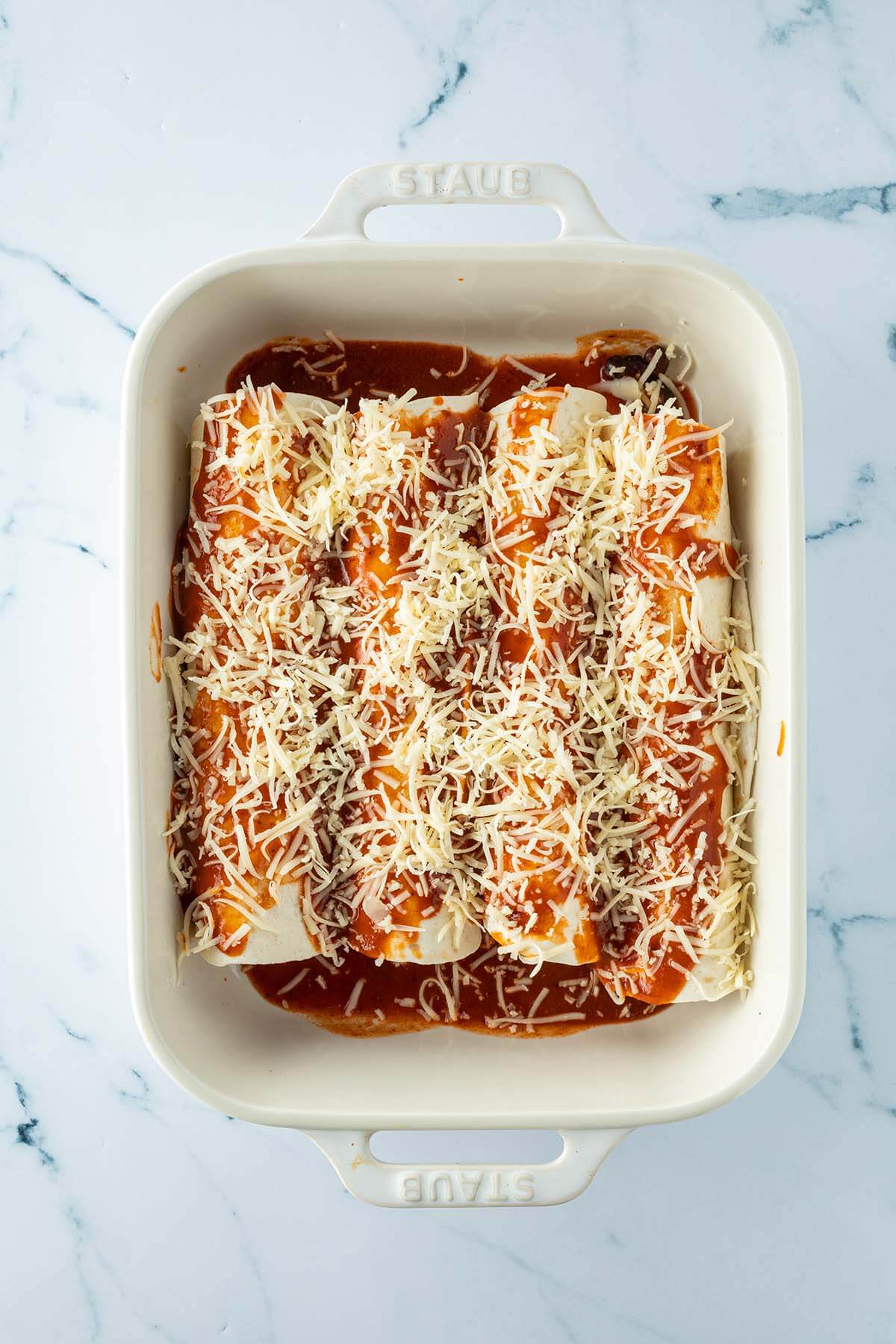 Enchiladas mit Sauce und geriebenem K&auml;se in einer Auflaufform.