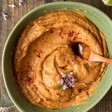 Sch&uuml;ssel mit cremiger Erdnusssauce, im Hintergrund eine Limette und ein Geschirrtuch.
