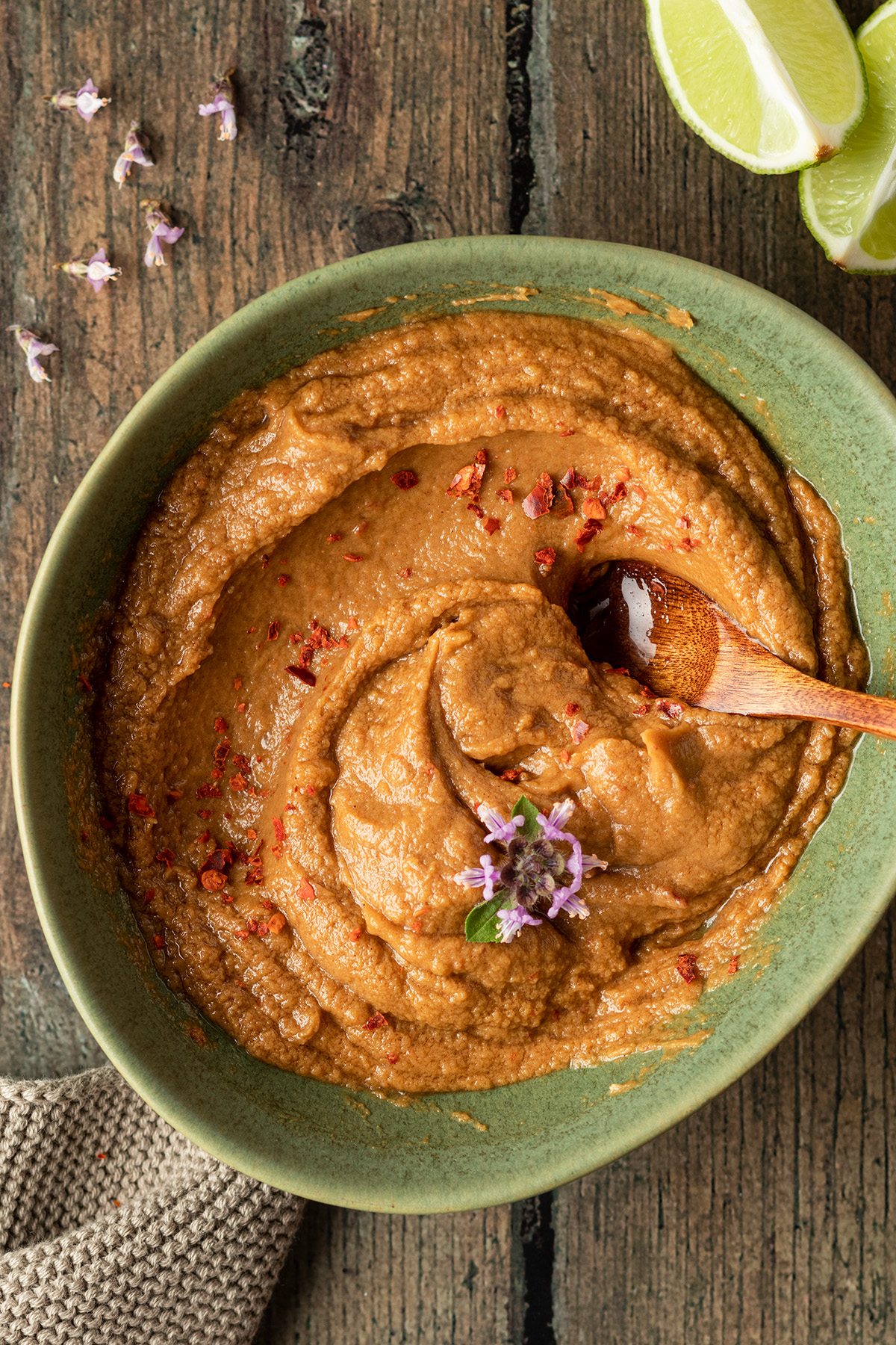 Sch&uuml;ssel mit cremiger Erdnusssauce, im Hintergrund eine Limette und ein Geschirrtuch.