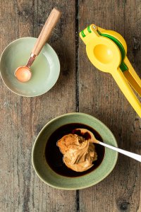 Eine Sch&uuml;ssel mit Erdnussbutter, Sojasauce und braunem Zucker, daneben eine Zitruspresse und eine zwei Sch&uuml;ssel mit Limettensaft gef&uuml;llt.