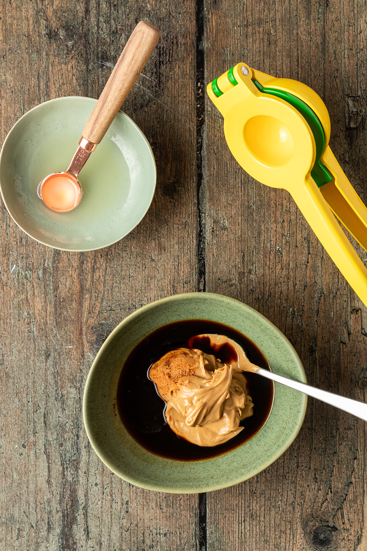 Eine Sch&uuml;ssel mit Erdnussbutter, Sojasauce und braunem Zucker, daneben eine Zitruspresse und eine zwei Sch&uuml;ssel mit Limettensaft gef&uuml;llt.
