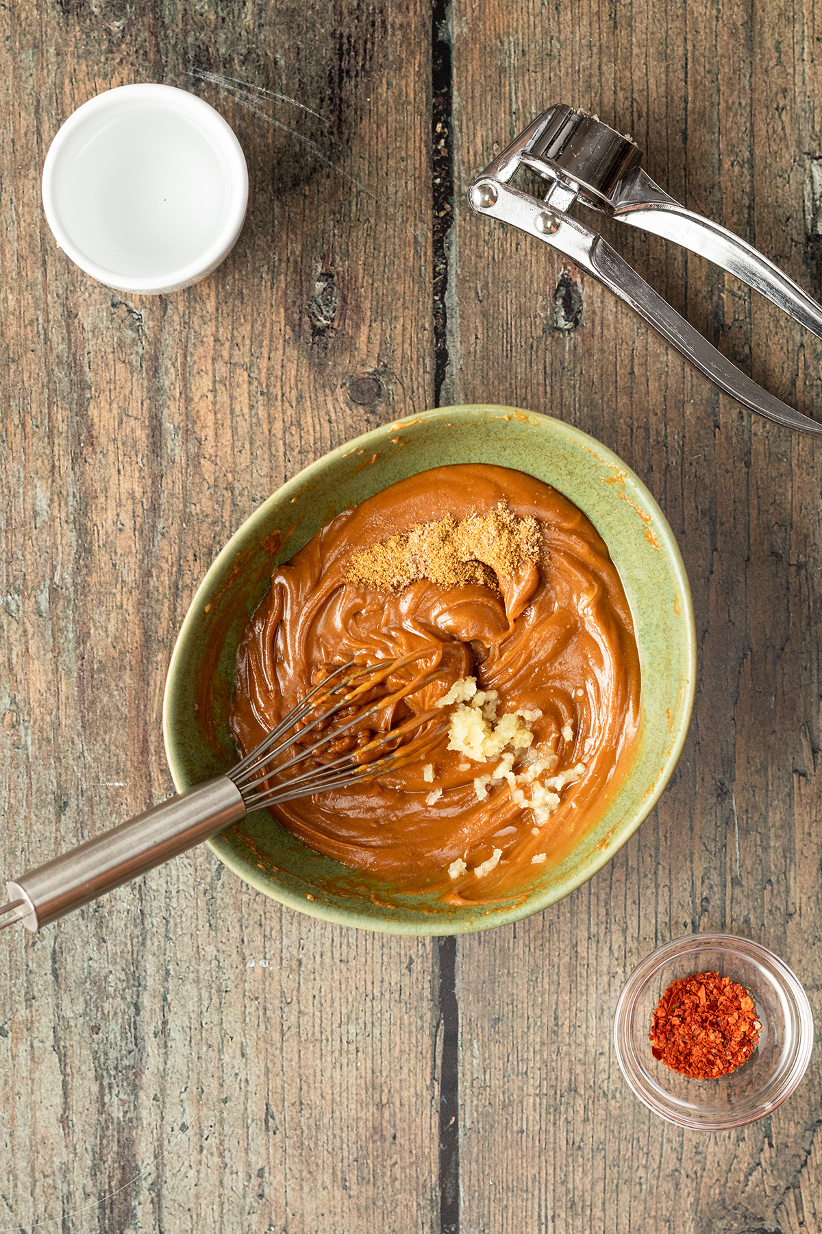 Erdnusssauce wird in einer Sch&uuml;ssel mit Knoblauch und den Gew&uuml;rzen verr&uuml;hrt.
