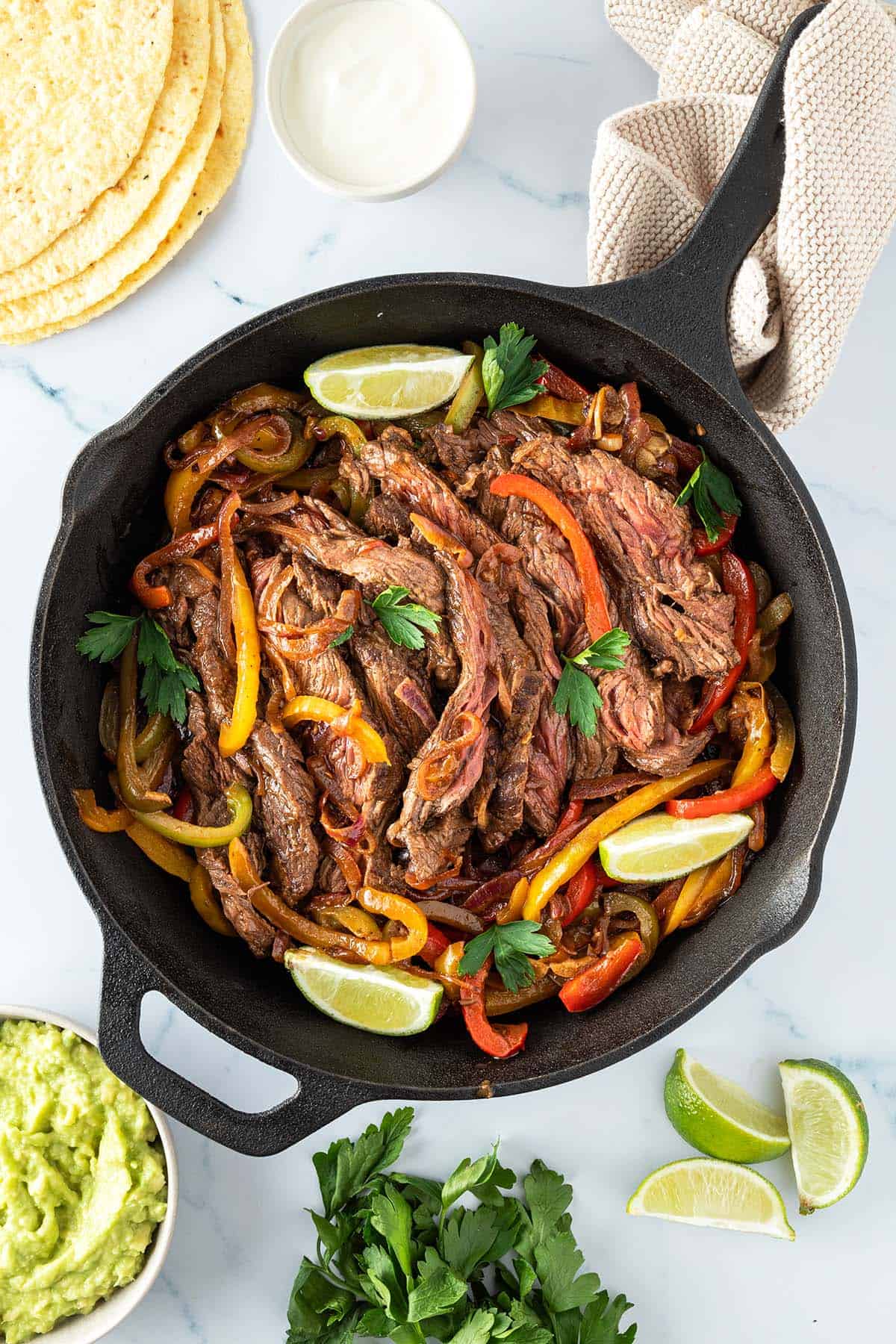 Fajitas Pfanne mit Rindfleisch serviert mit Tortillas, Sourcoream, Guacamole und Limette.