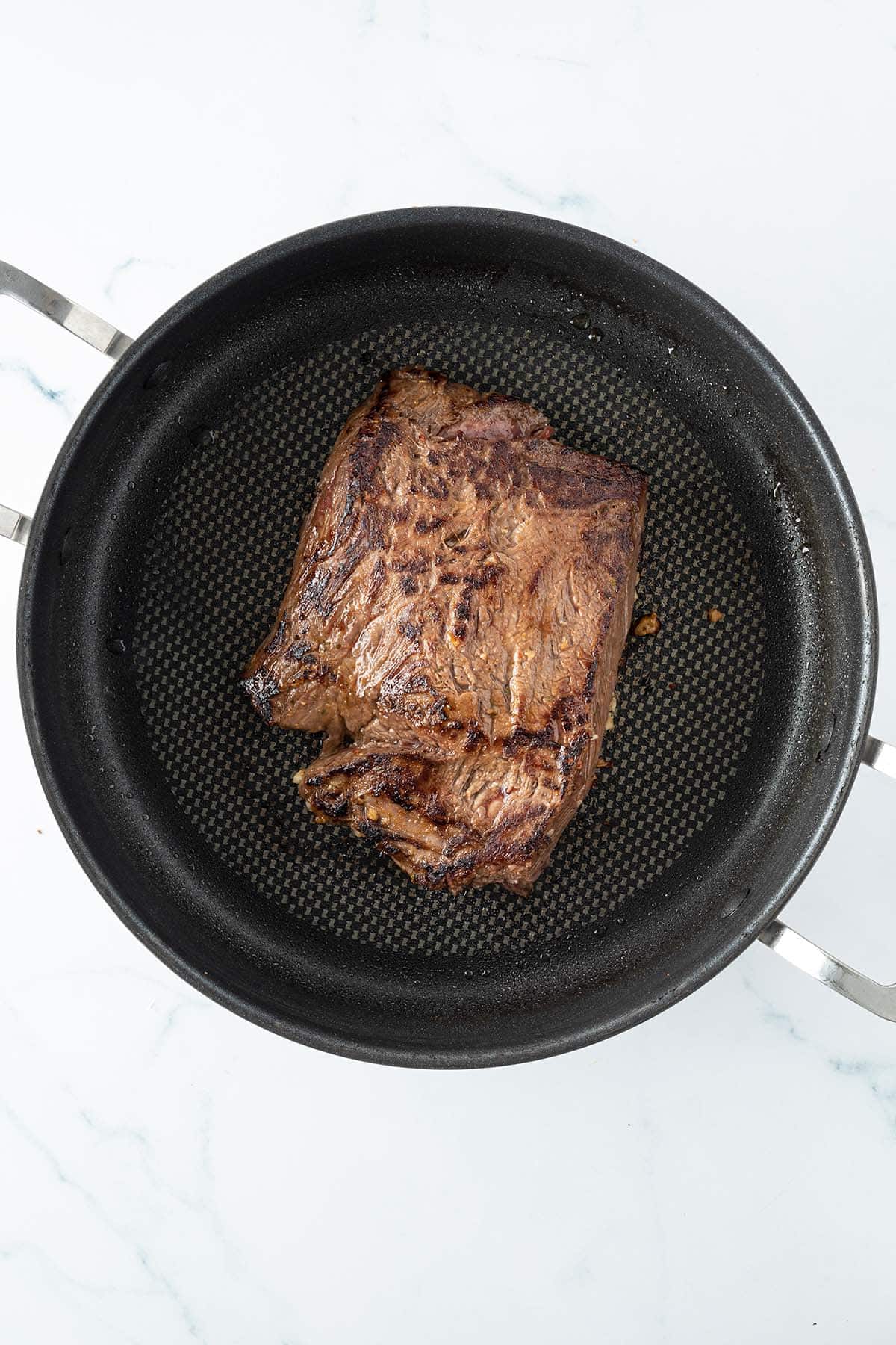 Ein angebratenes St&uuml;ck Steak in einer Pfanne.