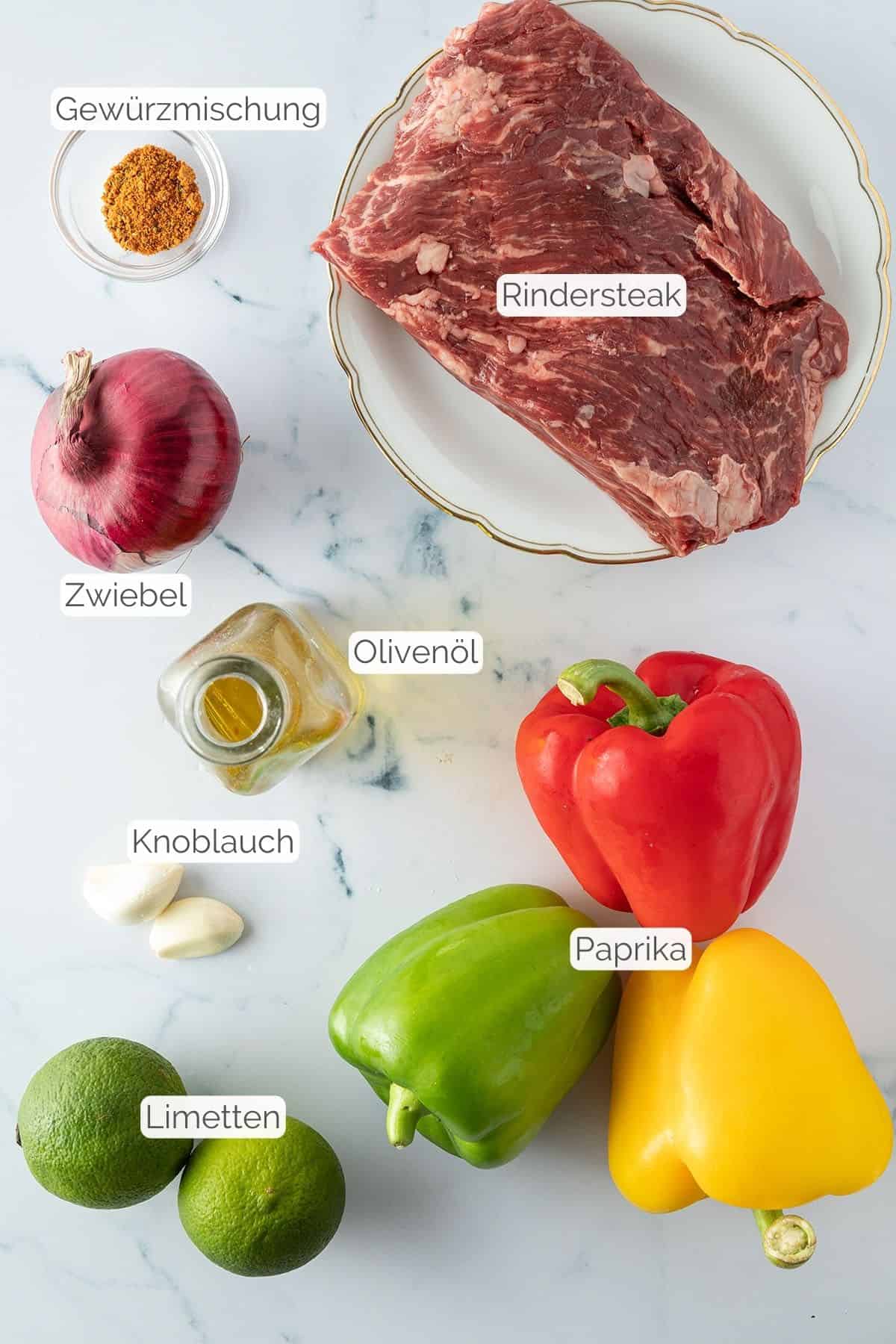 Alle Zutaten mit jeweiligen Textbeschriftungen, die f&uuml;r mexikanische Fajitas mit Rindfleisch ben&ouml;tigt werden.
