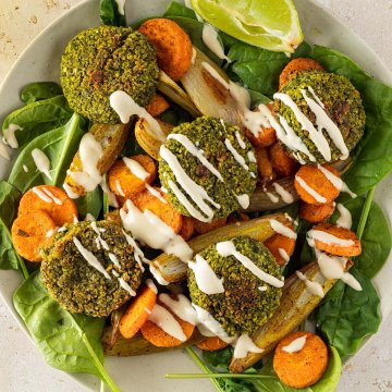 Vogelperspektive auf eine orientalische Bowl mit Falafel, Gemüse und einer hellen Sauce.