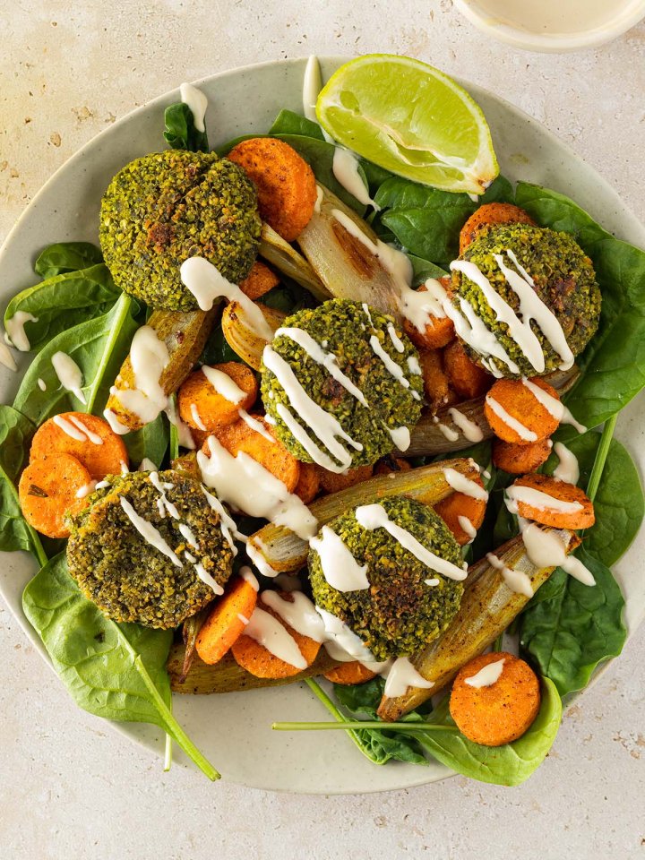 Vogelperspektive auf eine orientalische Bowl mit Falafel, Gemüse und einer hellen Sauce.