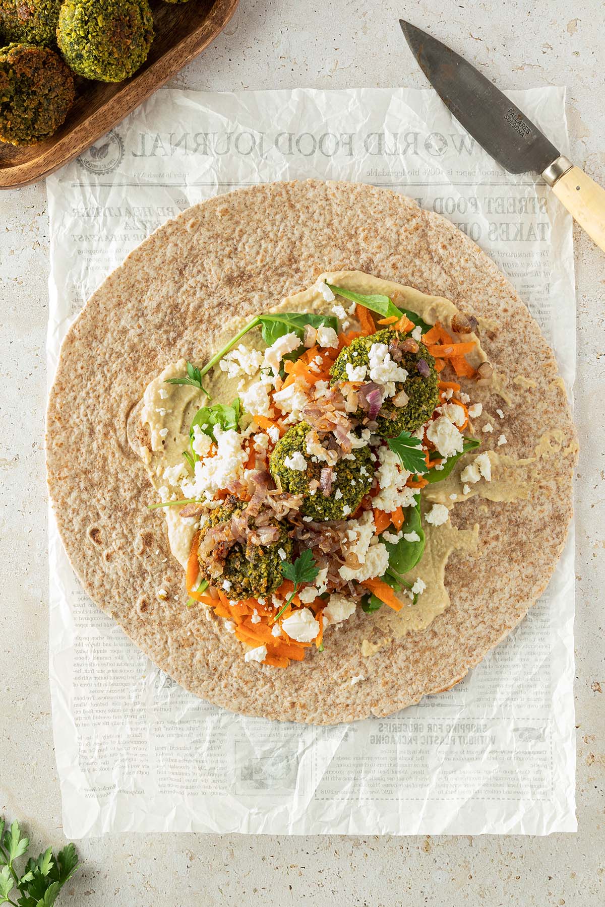 Ein offener Falafel Wrap auf hellem Untergrund mit Deko im Bildrand.