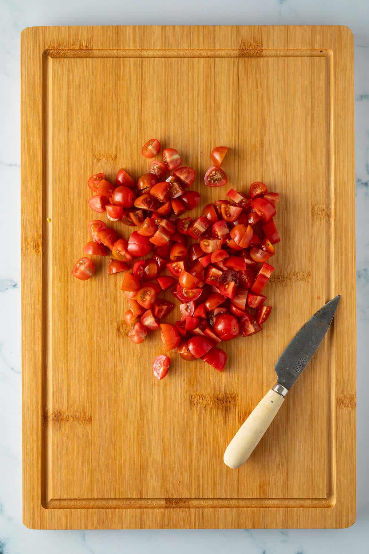 Klein gew&uuml;rfelte Tomaten auf einem Brett.