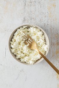 Zerkr&uuml;melter Feta in einer kleinen Sch&uuml;ssel mit einer Gabel.
