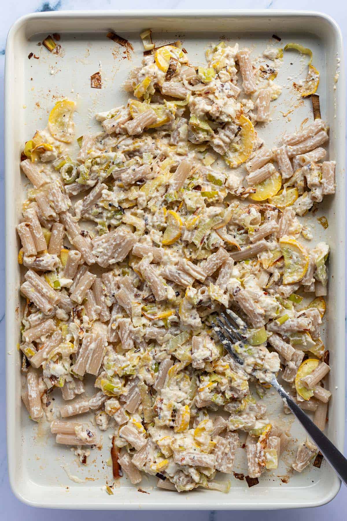 Gekochte Nudeln in einer cremigen Feta Sauce mit Gem&uuml;se auf einem Blech.