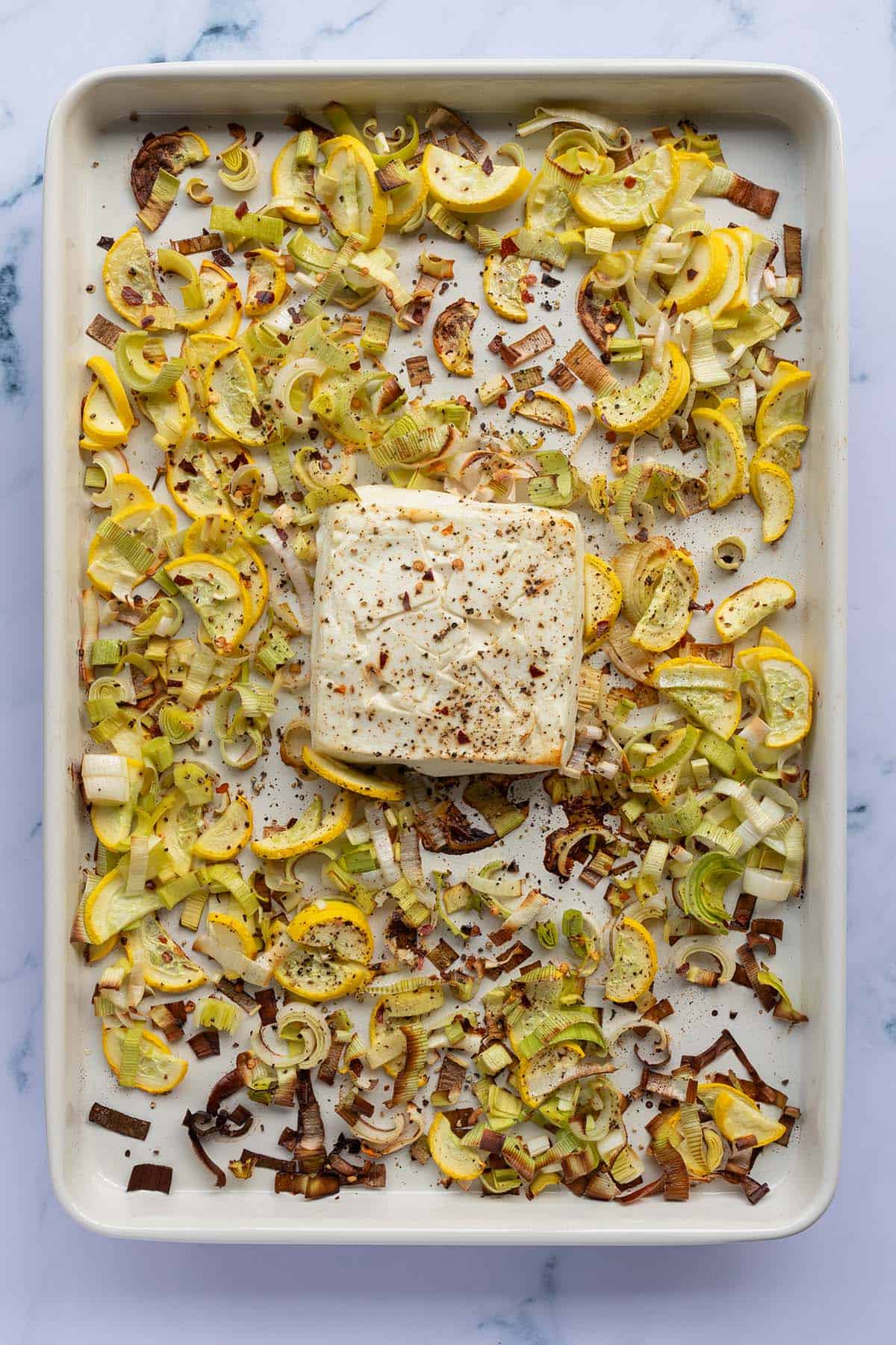 Im Ofen ger&ouml;stetes Gem&uuml;se und Feta auf einem Blech.