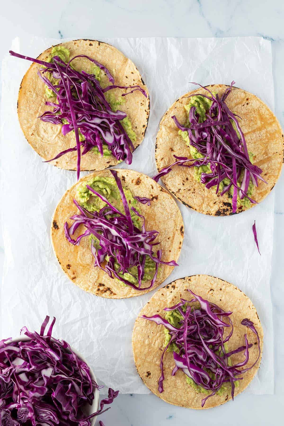 Vier Tacos mit Guacamole und d&uuml;nnen Rotkohl Streifen.