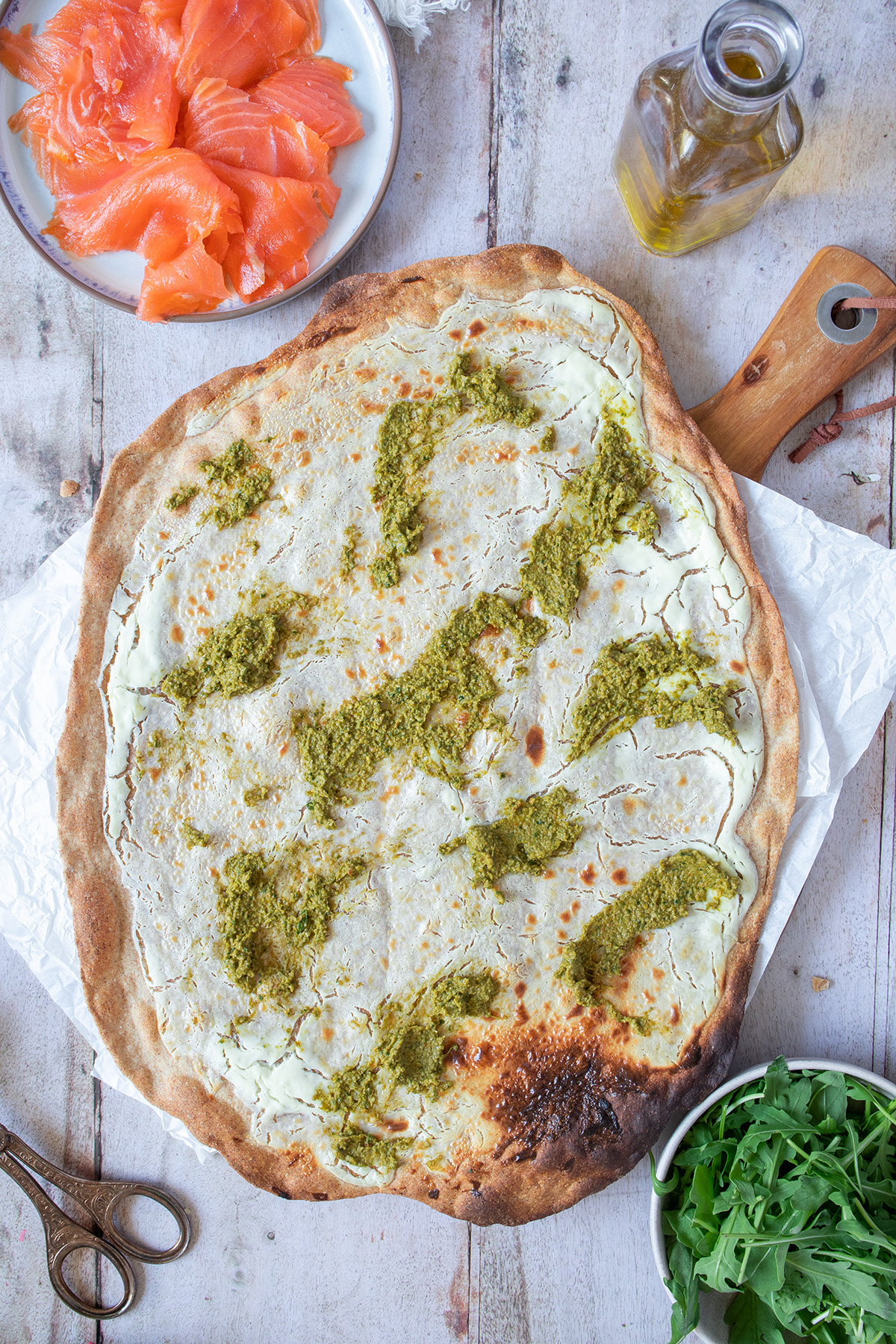 Gebackener Flammkuchenteig mit Pesto drauf.