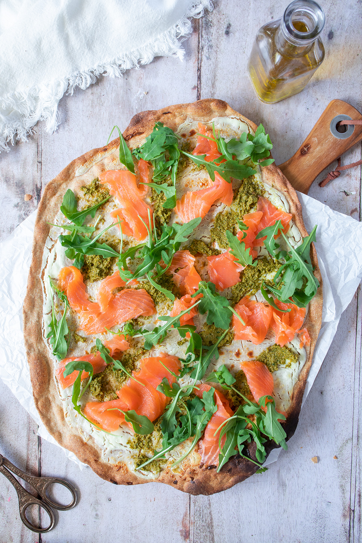 Flammkuchen mit R&auml;ucherlachs, Rucola und gr&uuml;nem Pesto.