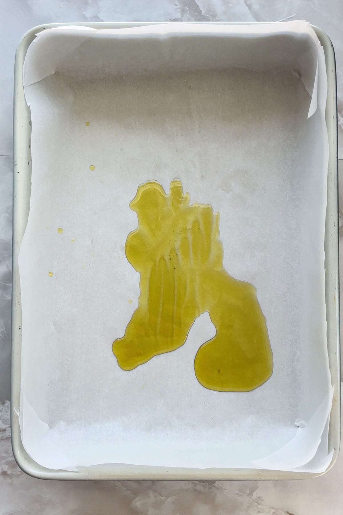 Oliven&ouml;l in einer mit Backpapier ausgelegten Backform.