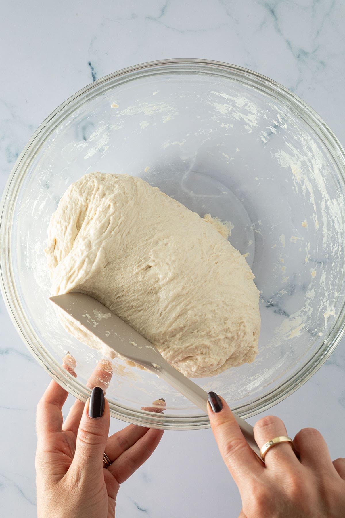 Focaccia-Teig wird nach 30 Minuten mit einem Teigschaber in einer Glassch&uuml;ssel gefaltet.