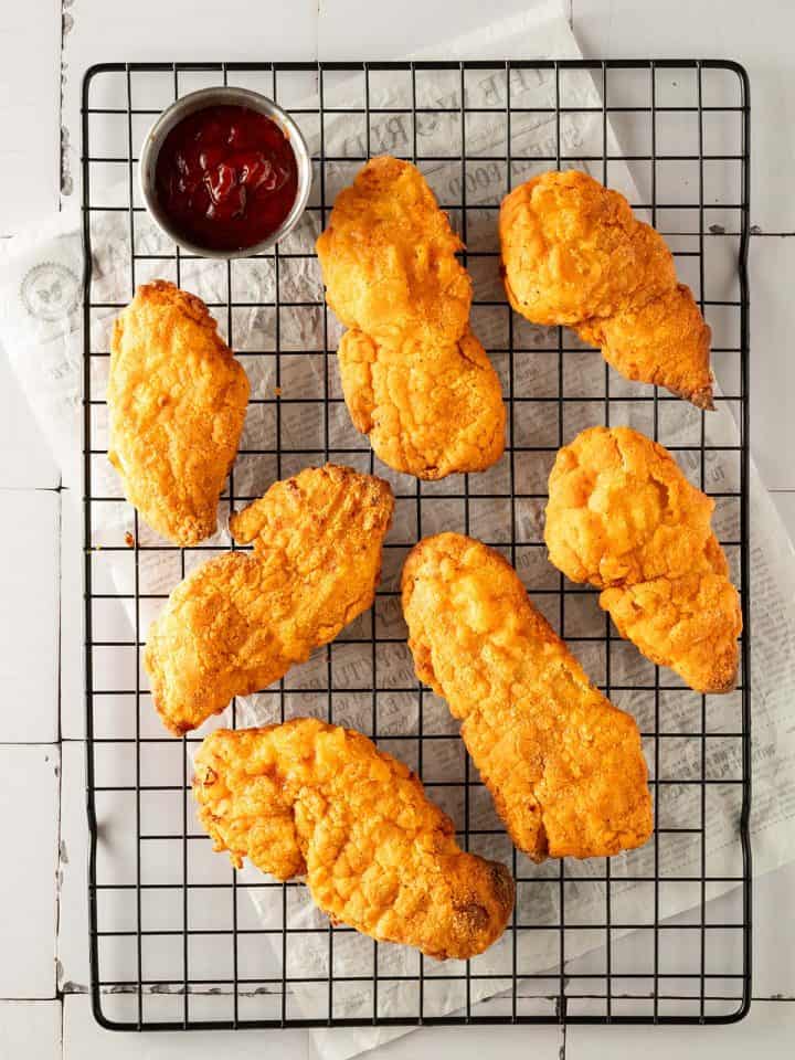 Knuspriges Fried Chicken aus dem Airfryer mit Ketchup auf einem Gitter.