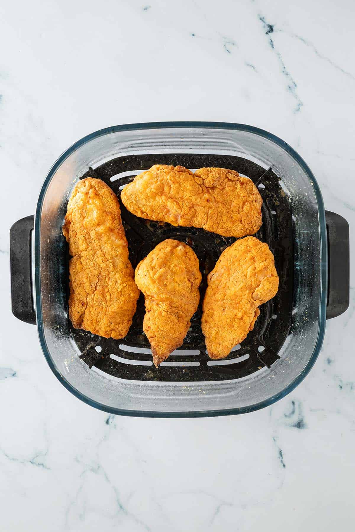 Goldbraun gebackenes Fried Chicken im Korb des Airfryers.