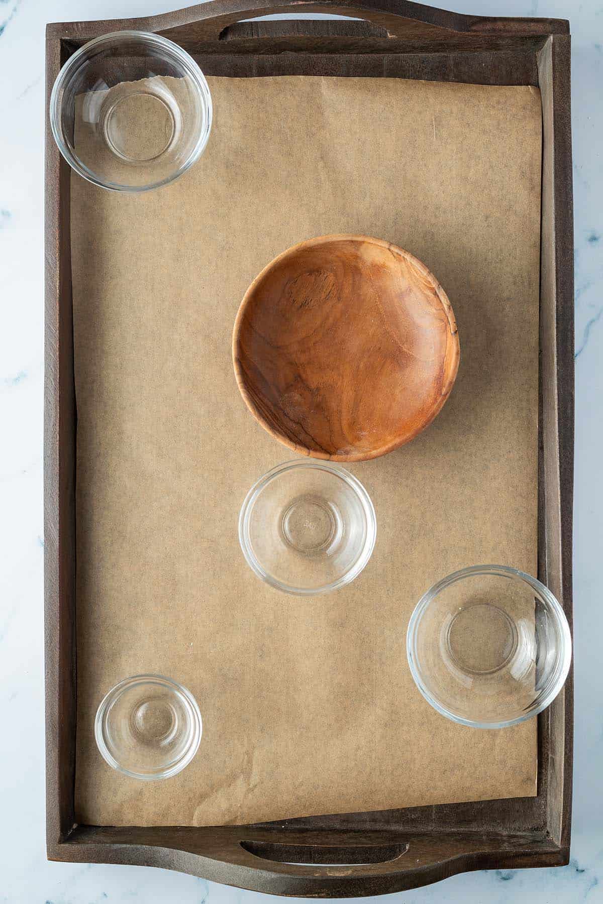 Holztablett mit f&uuml;nf leeren, kleinen Sch&uuml;sseln.