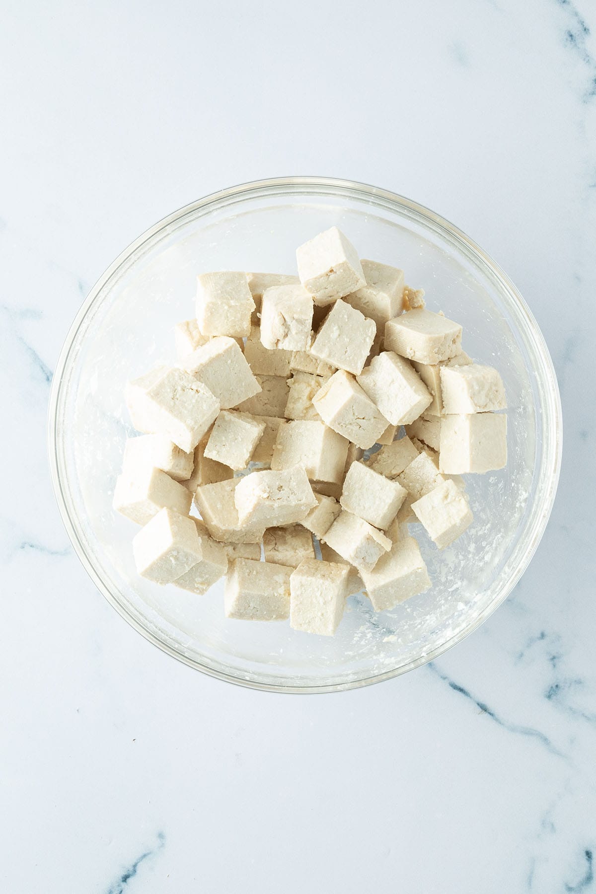 Mit Stärke und Öl marinierte Tofu-Würfel in einer Schüssel.