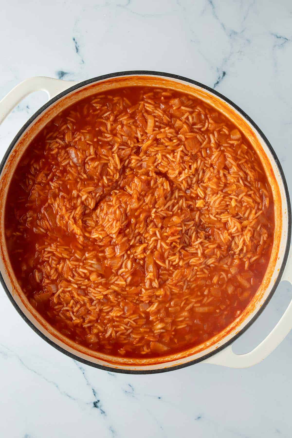 Gekochter Reis in einer tiefen Pfanne mit Tomatensauce.