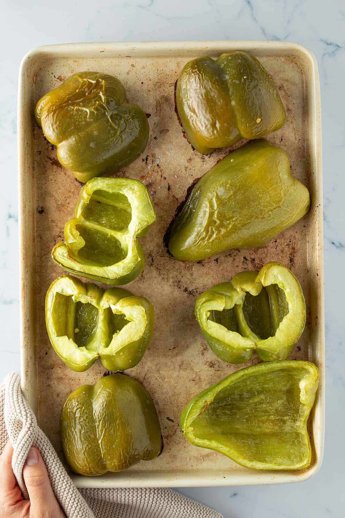 Ger&ouml;stete Paprika-H&auml;lften auf einem Blech.