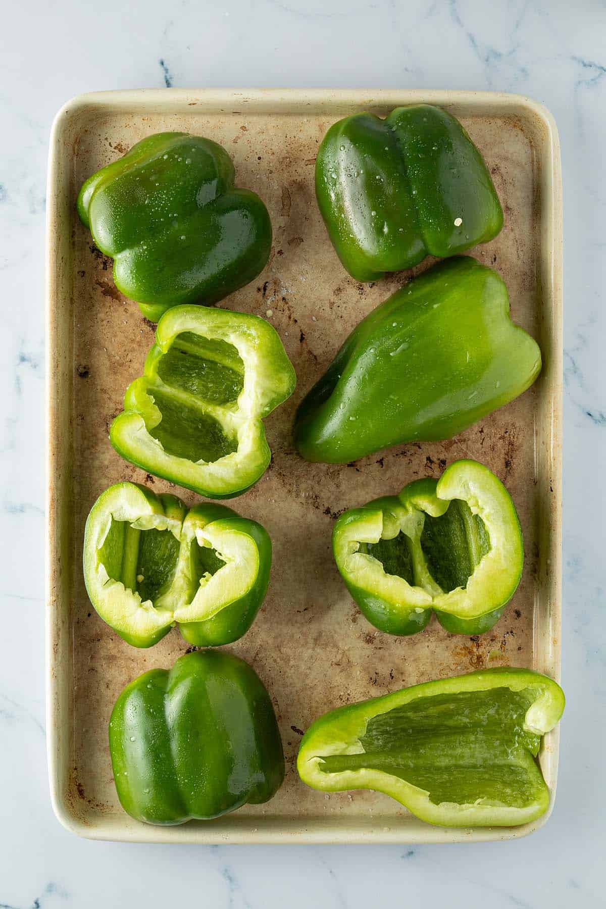 Halbierte Paprikaschoten auf einem Blech.