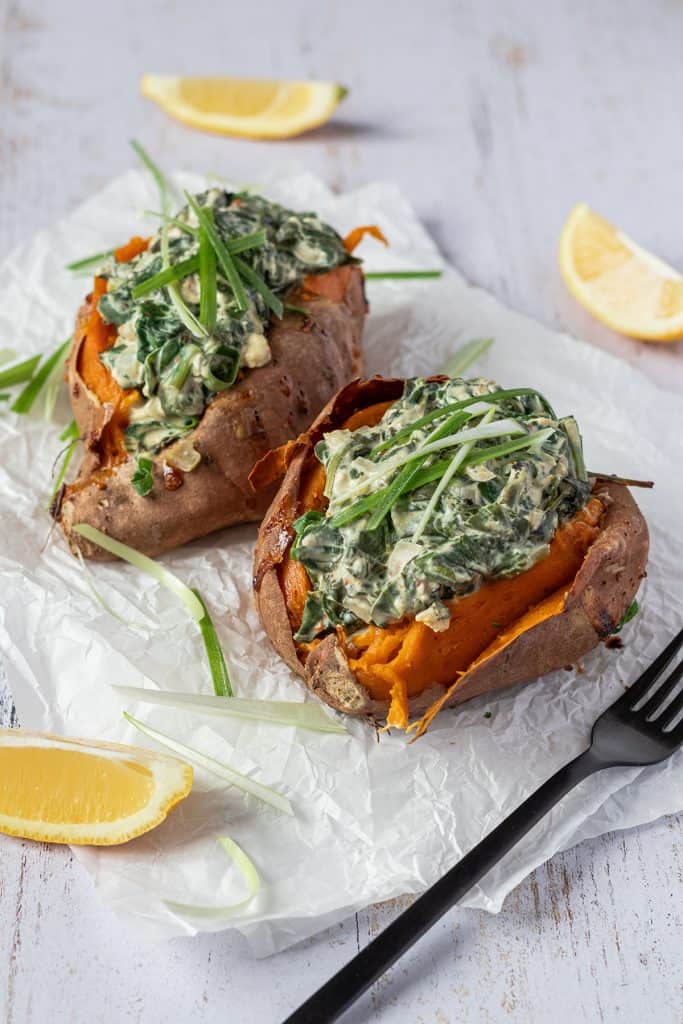 Zwei mit Spinat und Feta gef&uuml;llte S&uuml;&szlig;kartoffeln auf einem Butterpapier.