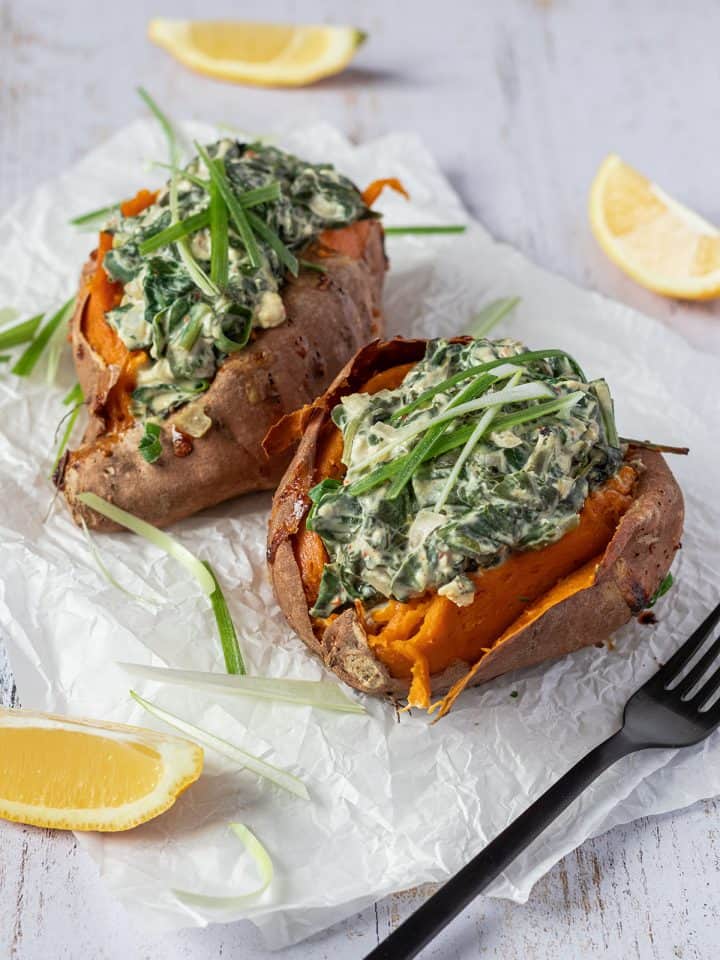Zwei mit Spinat und Feta gef&uuml;llte S&uuml;&szlig;kartoffeln auf einem Butterpapier.