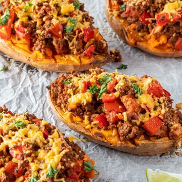 Gefüllte Süßkartoffeln mit einer Hackfleisch-Paprikapfanne und geschmolzenem Käse auf einem Blech.