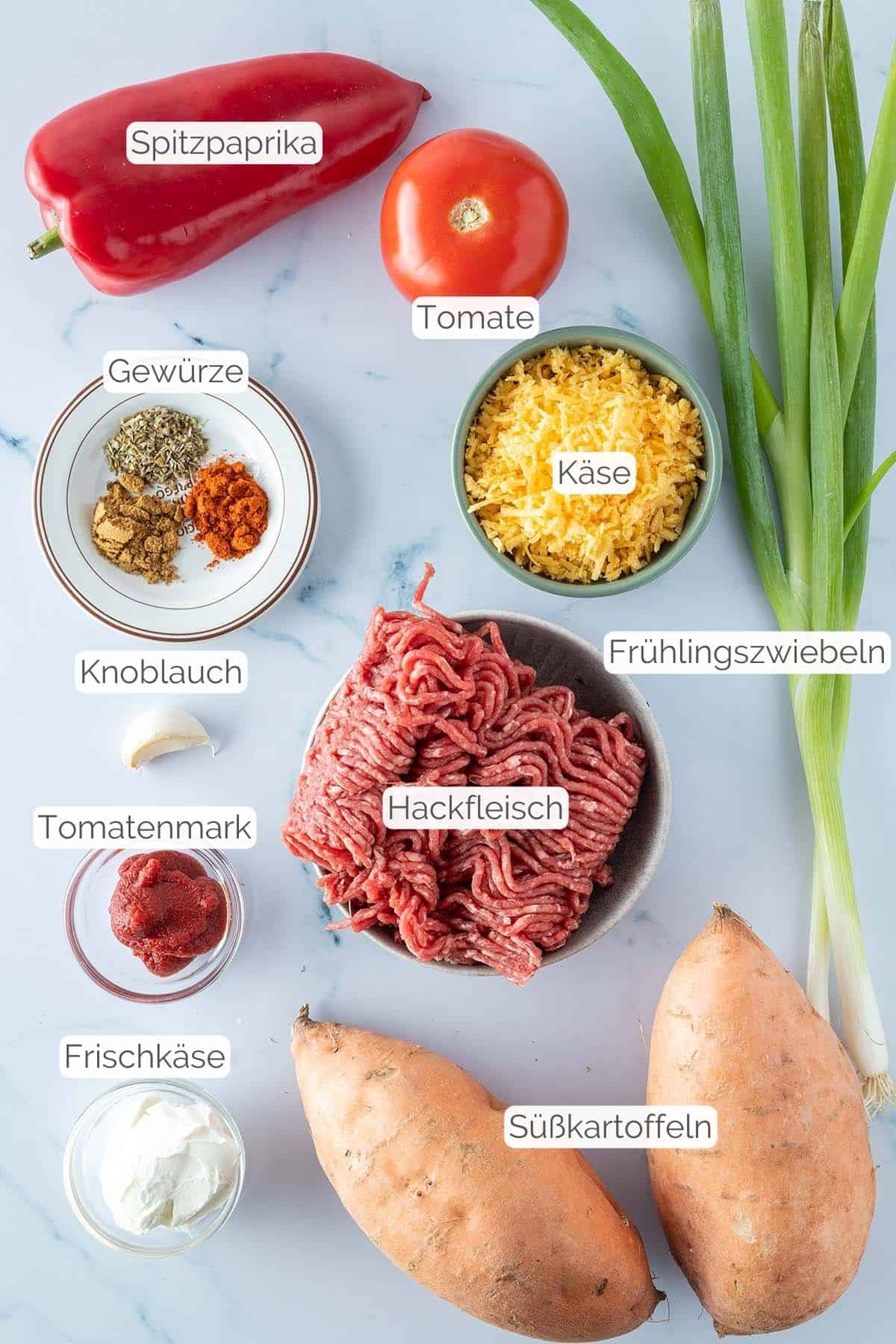 Alle Zutaten mit jeweiligen Textbeschriftungen, die für die mit Hackfleisch gefüllten Süßkartoffeln benötigt werden.