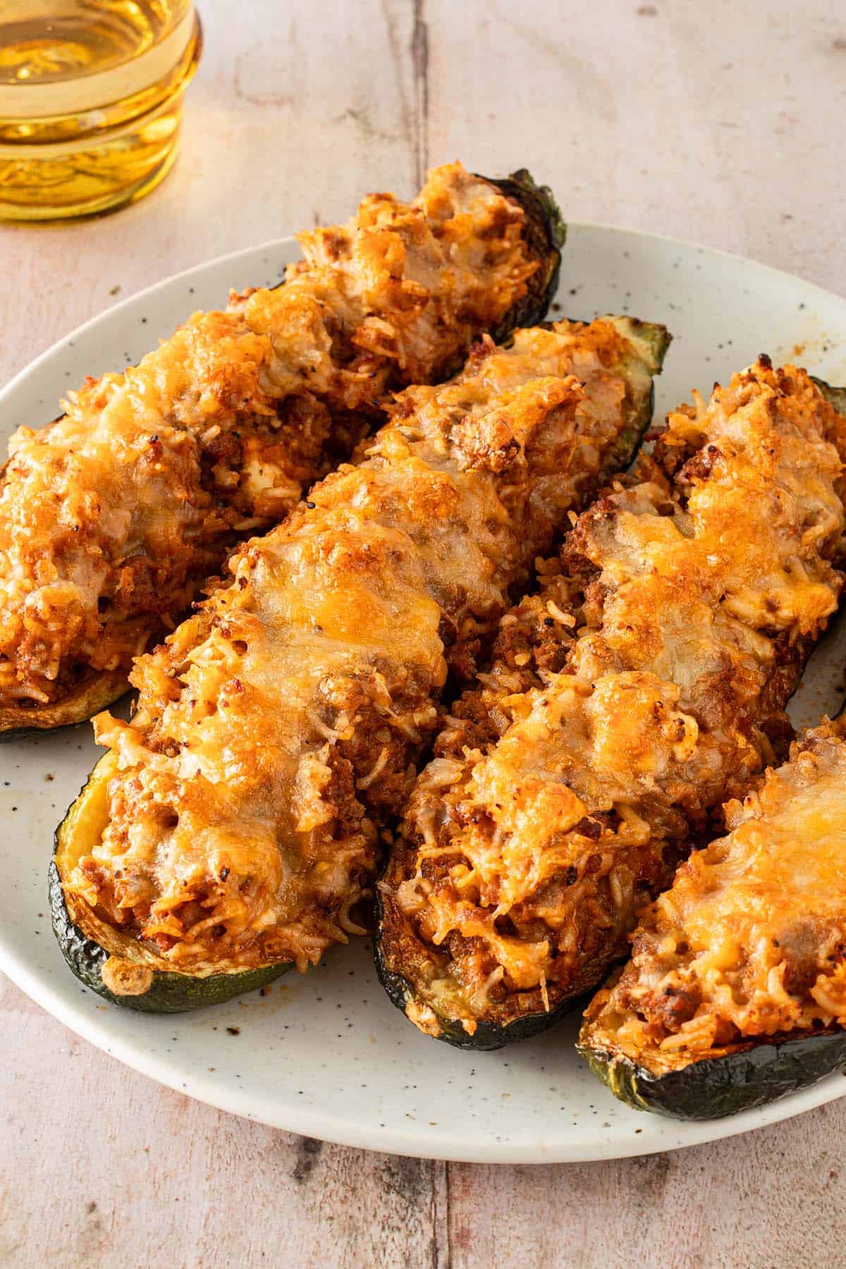 &Uuml;berbackene, gef&uuml;llte Zucchinih&auml;lften mit Reis, Hackfleisch und geschmolzenem K&auml;se auf einem Teller serviert.