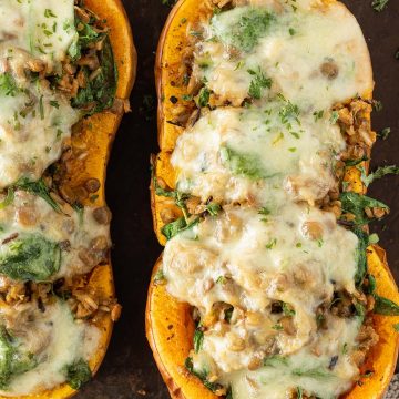Gef&uuml;llte und mit K&auml;se &uuml;berbackene Butternut K&uuml;rbish&auml;lften auf einem rustikalen Blech.