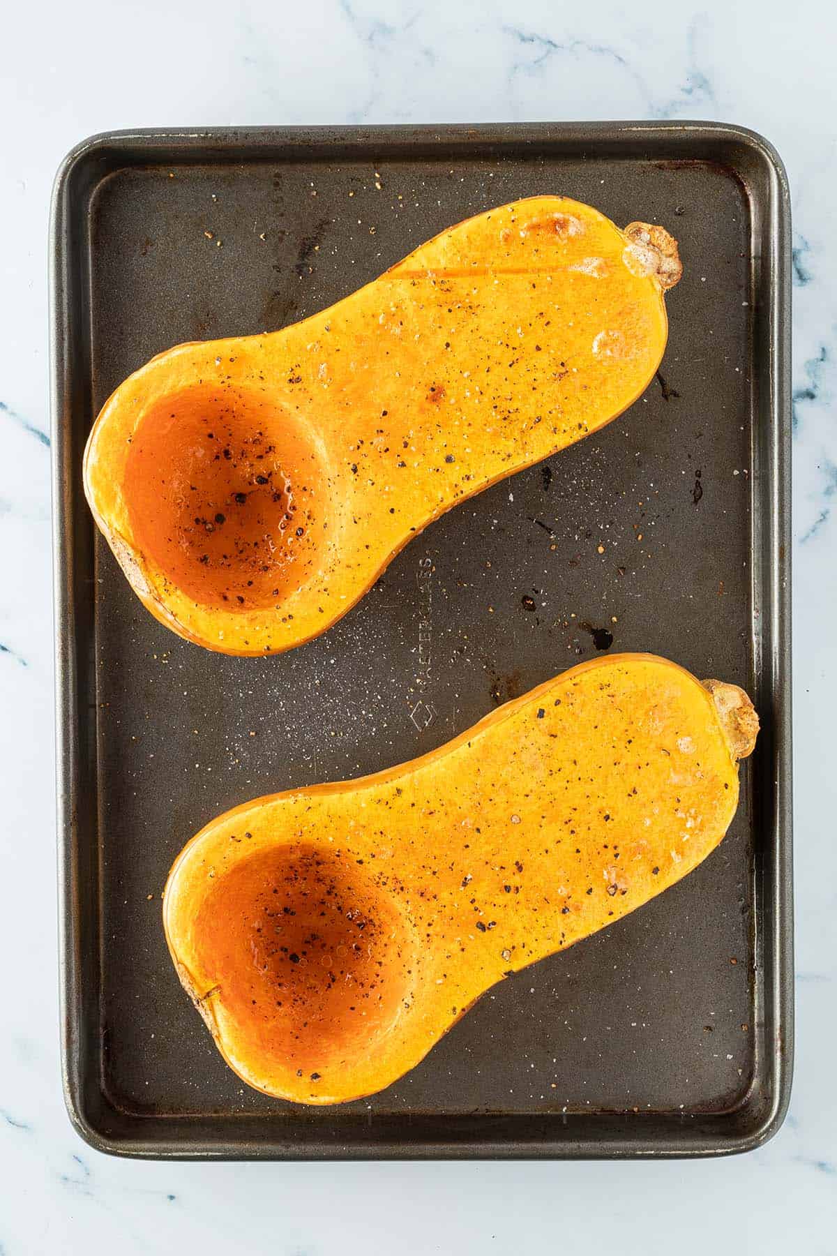 Zwei weich ger&ouml;stete Butternut K&uuml;rbish&auml;lften auf einem Blech.