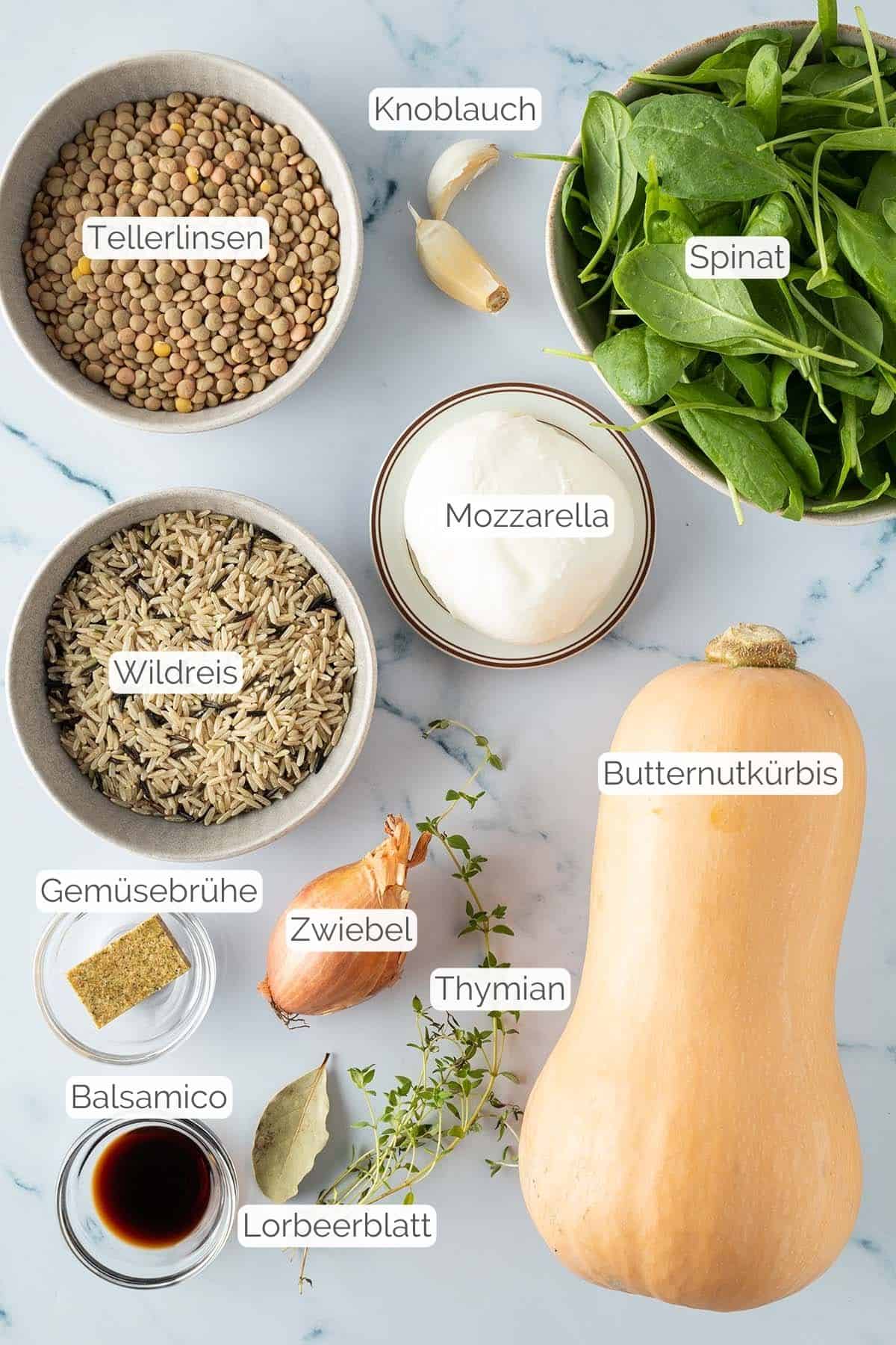 Alle Zutaten mit jeweiligen Textbeschriftungen, die f&uuml;r den vegetarisch gef&uuml;llten K&uuml;rbis ben&ouml;tigt werden.