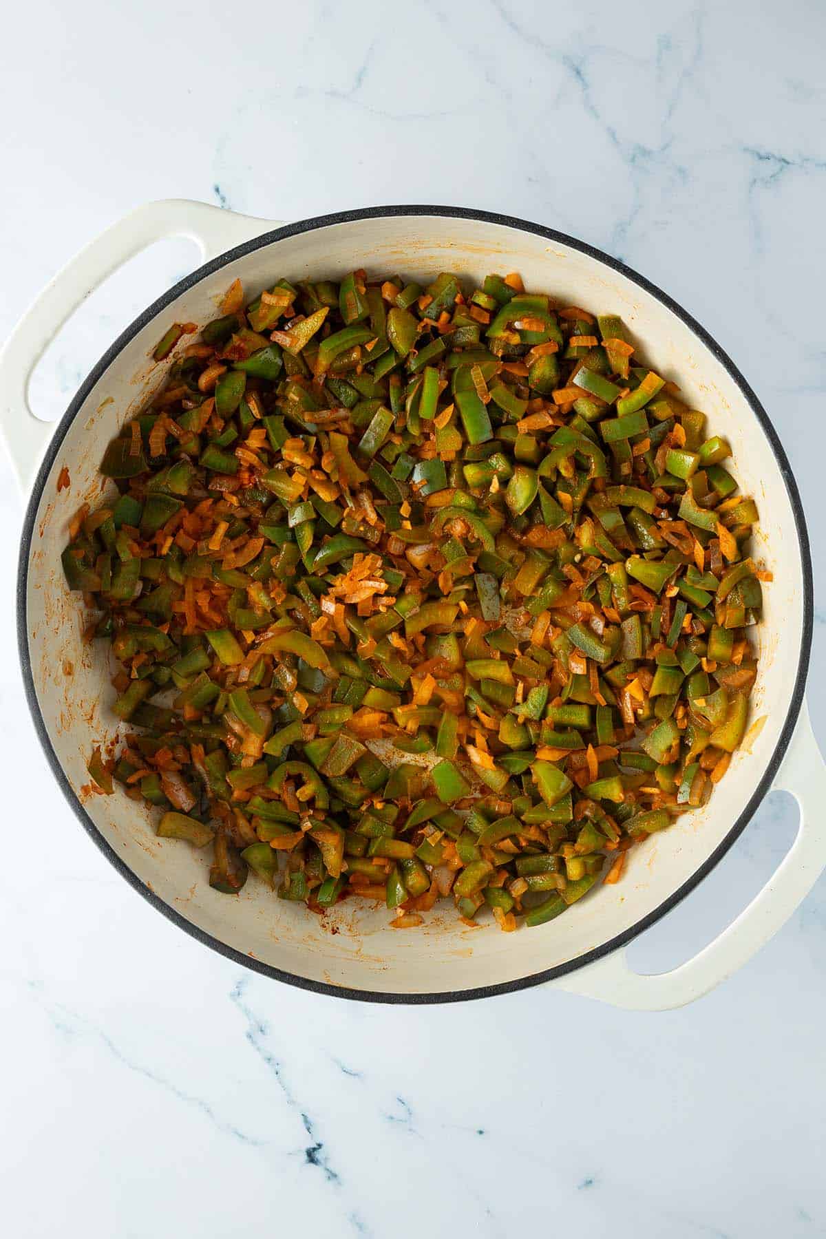 Paprika, Zwiebeln, Knoblauch, Chili und Gew&uuml;rze in einer Pfanne.