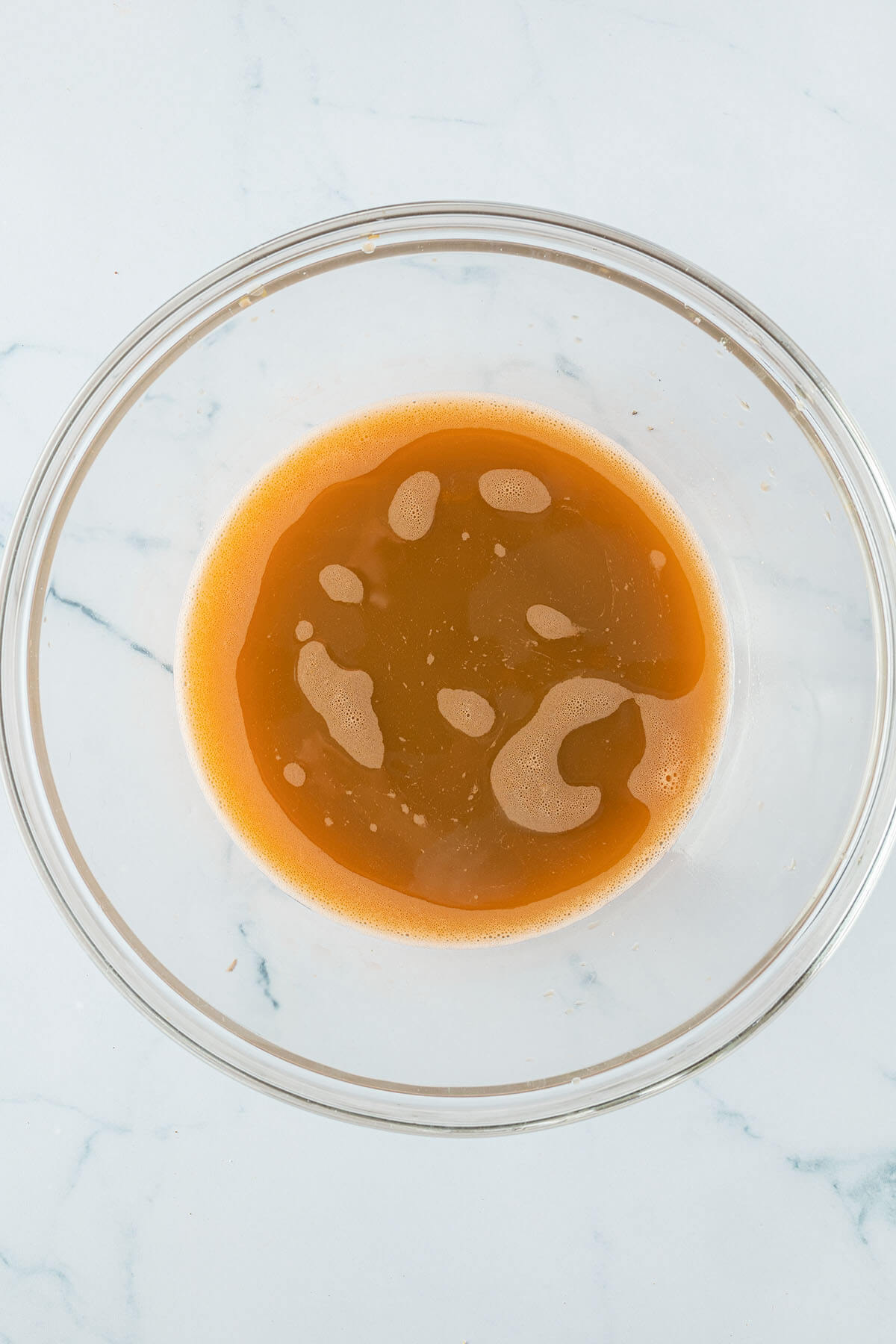 Vogelperspektive auf eine Glassch&uuml;ssel mit dem aufgefangenen Saft der ausgepressten Gem&uuml;seraspeln.