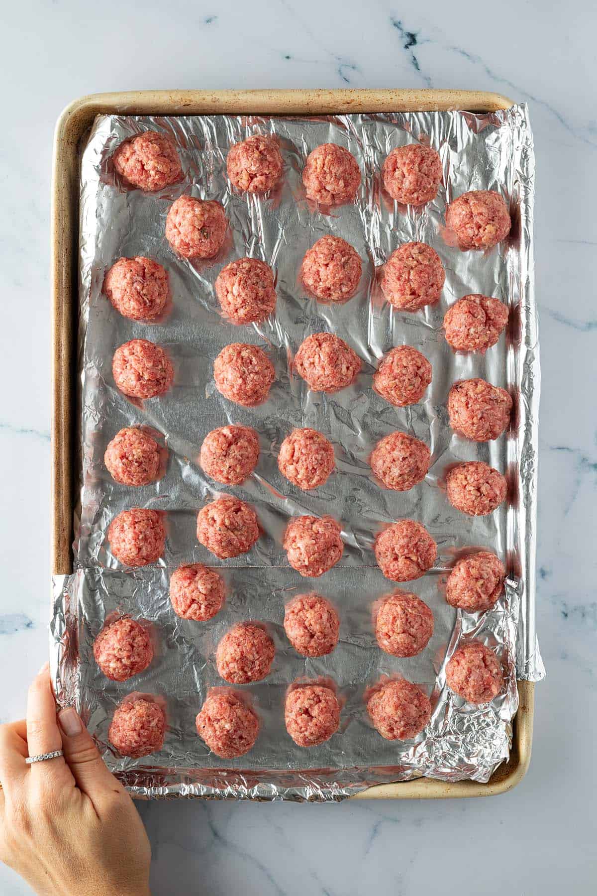 Kleine Hackb&auml;llchen auf einem Blech mit Alufolie.