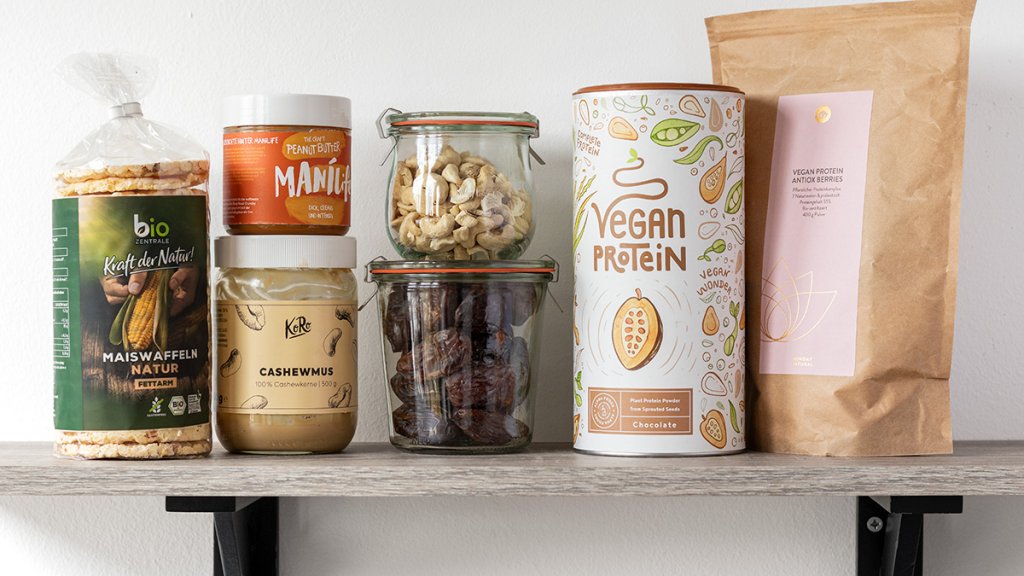 Gesunde Lebensmittel f&uuml;r die Vorratskammer zum Snacken: Maiswaffeln, Nussmus, N&uuml;sse, getrocknete Fr&uuml;chte, veganes Proteinpulver